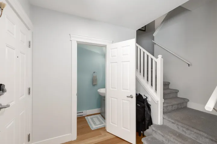 Staircase with wood finished floors and a baseboard heating unit