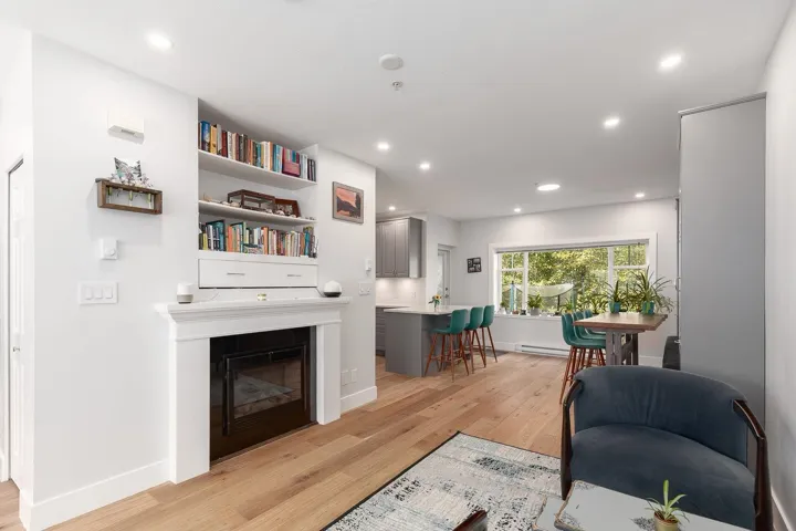 Living area with light wood-type flooring, a glass covered fireplace, recessed lighting, and a baseboard radiator