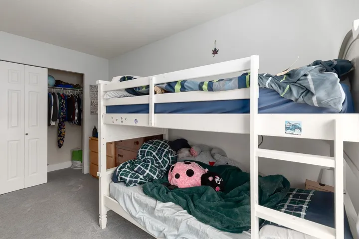 Carpeted bedroom with a closet and baseboards