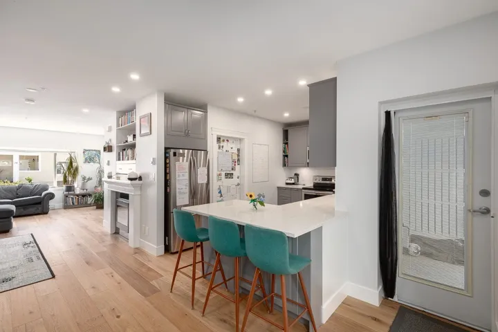 Kitchen featuring gray cabinetry, open shelves, appliances with stainless steel finishes, a peninsula, and light wood-style floors