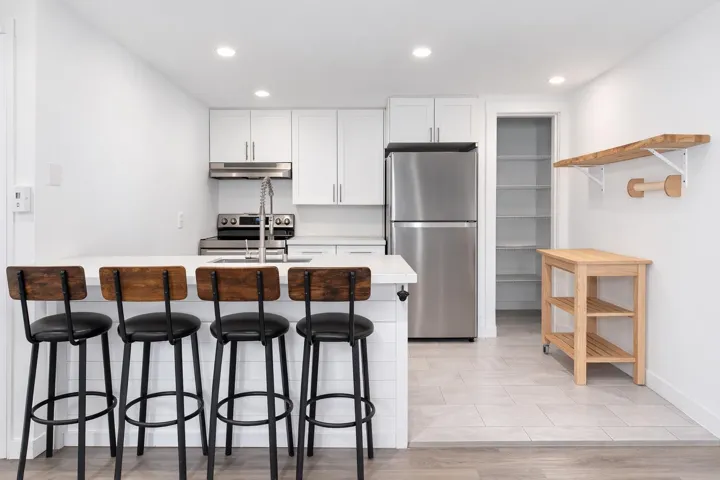 Kitchen featuring white cabinetry, a kitchen bar, stainless steel appliances, open shelves, and recessed lighting