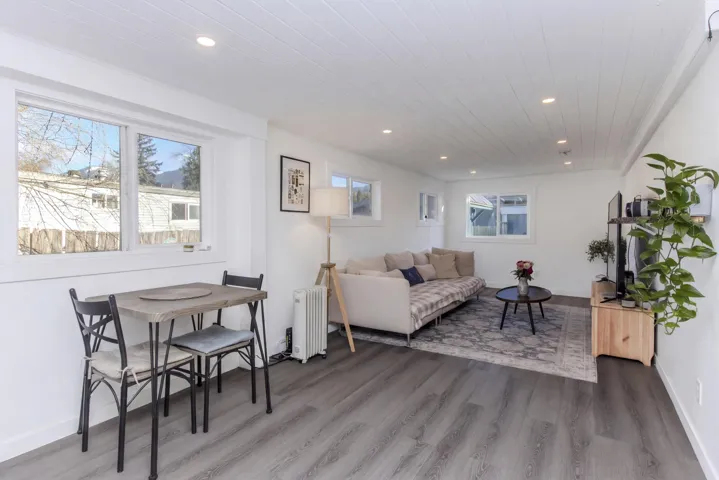 Living area with light wood-style flooring, radiator heating unit, recessed lighting, and wood ceiling