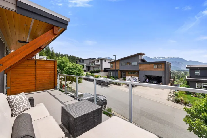 Private balcony with glass railing, modern wood ceiling details, and a slatted wood privacy wall