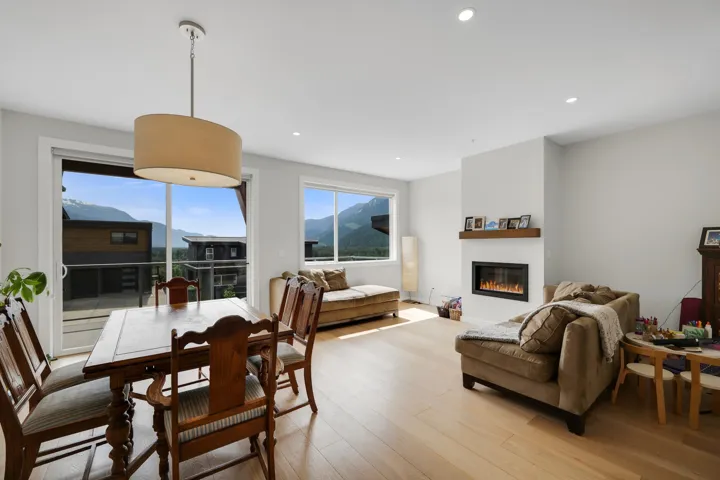 Open concept living space featuring wood-finish flooring, a contemporary fireplace with a wood mantle, and recessed lighting