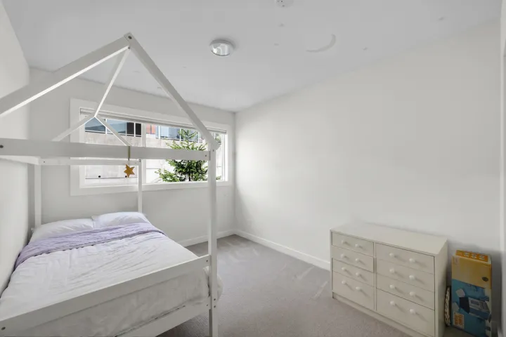 Bright room featuring a large window, light gray carpet, and white walls