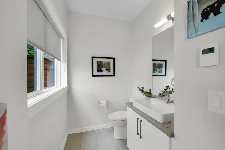 Bathroom with a rectangular vessel sink, wall-mounted mirror, and vanity lighting