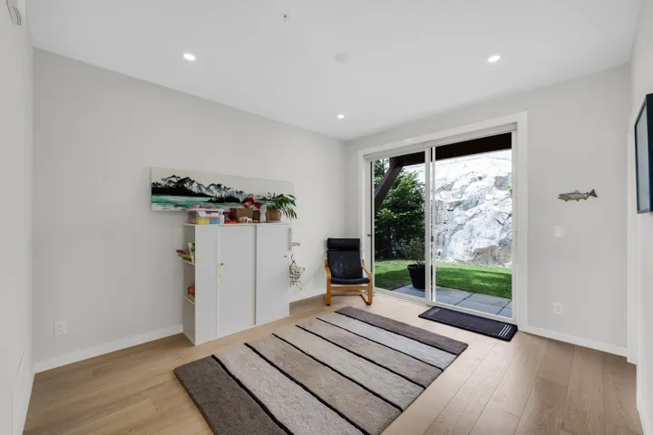 Spacious room featuring light wood-finish flooring, recessed lighting, and a large sliding glass door