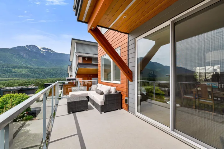 Exterior balcony featuring a glass railing, concrete flooring, and an expansive mountain backdrop