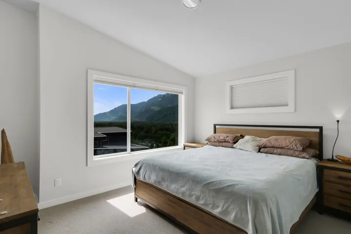 Bright interior space with a large picture window, vaulted ceiling, and neutral-toned wall paint