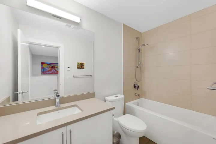 Bathroom featuring a vanity with an integrated sink, polished chrome faucet, white cabinetry, and light-toned countertop