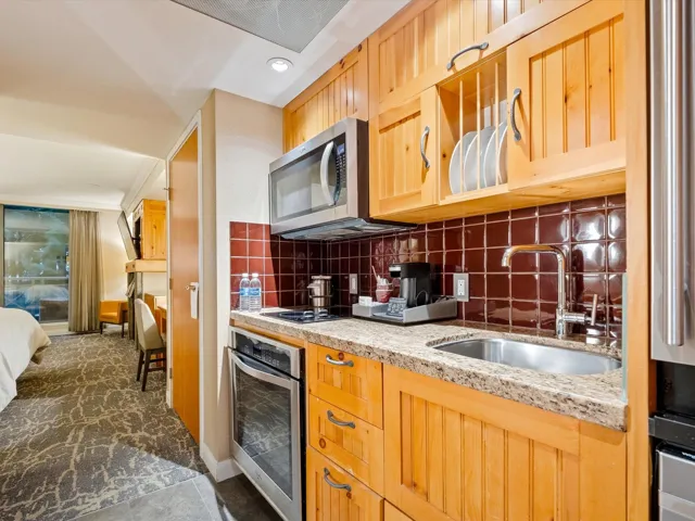 Kitchen featuring a sink, light stone countertops, stainless steel appliances, light brown cabinetry, and backsplash