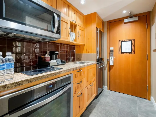 Kitchen featuring light stone counters, appliances with stainless steel finishes, a sink, backsplash, and recessed lighting