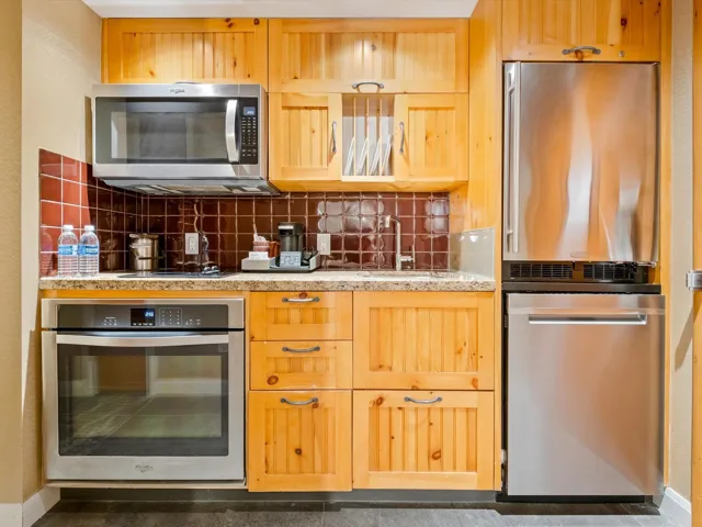 Kitchen featuring light stone counters, stainless steel appliances, tasteful backsplash, a sink, and baseboards