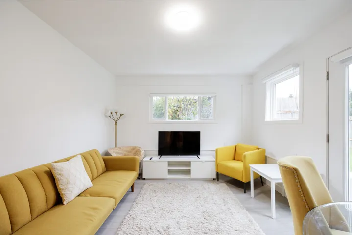 Neutral interior space featuring white walls, wood-finish flooring, and multiple windows with white trim