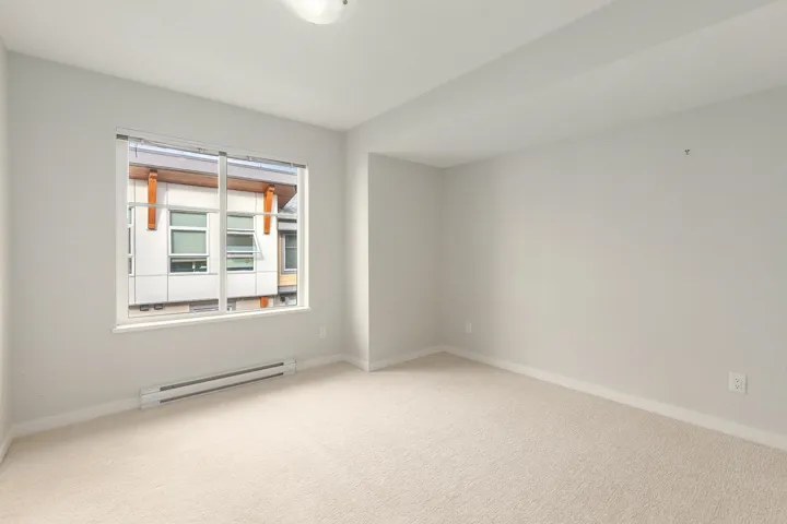 Bright room featuring a large window, neutral carpeting, and light-colored walls