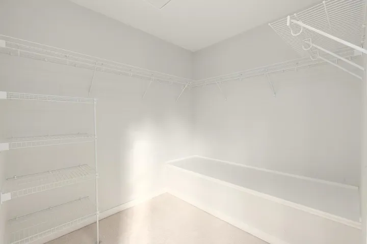 Walk-in closet featuring wire shelving, a built-in bench, and light-colored carpeting