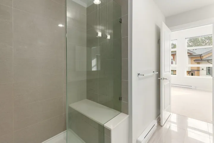 Glass-enclosed shower with a built-in bench and recessed lighting