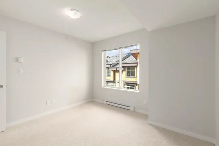 Carpeted room with a double-pane window, baseboard heating, and a flush-mount ceiling light