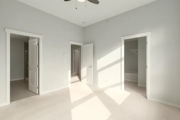 Spacious room featuring neutral carpet flooring, light gray wall paint, and white trim throughout