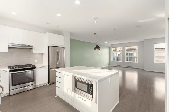 Modern kitchen featuring white cabinetry, stainless steel appliances, and a central island with an integrated microwave