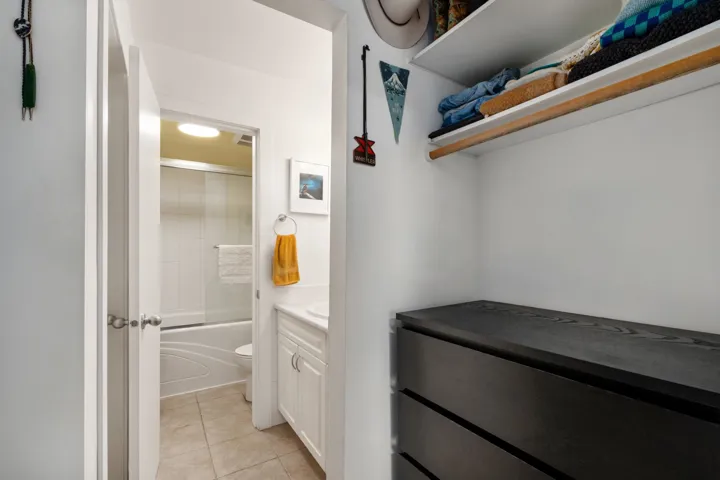 Wardrobe storage featuring built-in shelving, a clothes rod, and a dark wood-finish dresser