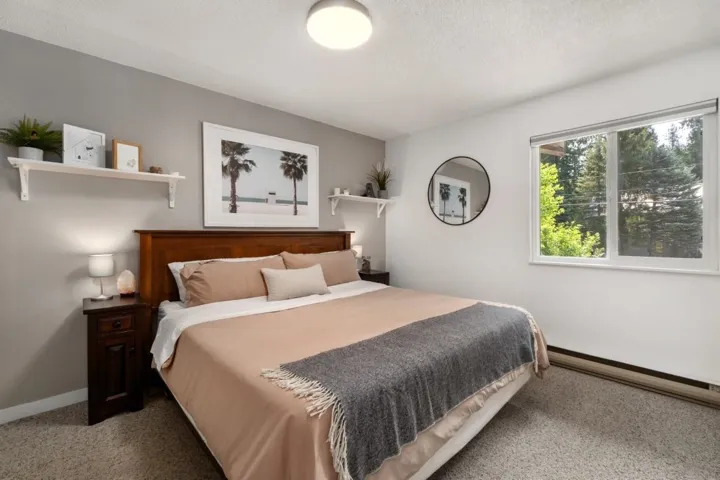Spacious room with a large window, a warm wood headboard, and light gray walls
