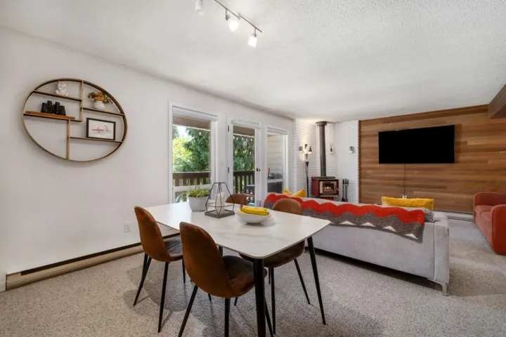 Spacious living area featuring a wood-panel accent wall, white brick detailing, and a freestanding fireplace