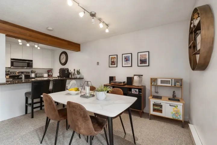 Open-concept dining area with track lighting and a kitchen pass-through
