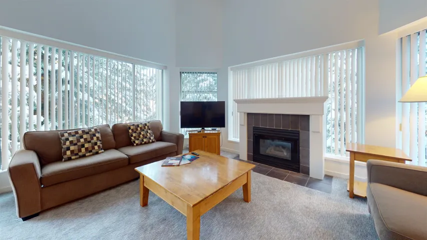 Living room with a fireplace, carpet flooring, and a towering ceiling