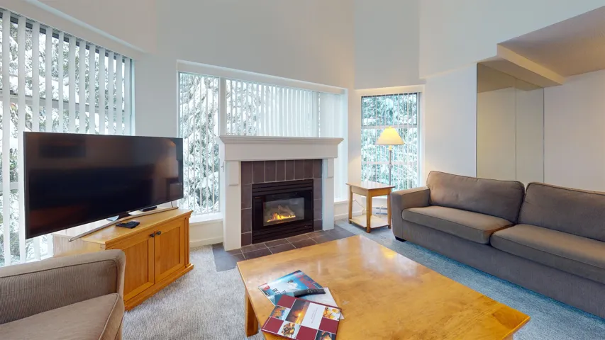 Living area featuring carpet, a fireplace, and a towering ceiling