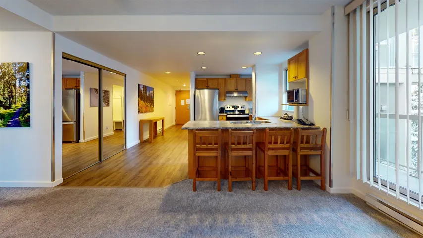 Kitchen with brown cabinetry, a peninsula, stainless steel appliances, a breakfast bar, and recessed lighting