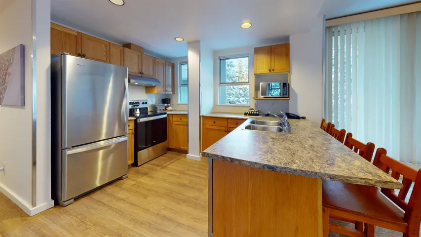 Kitchen featuring a kitchen breakfast bar, a peninsula, stainless steel appliances, recessed lighting, and light wood-style floors