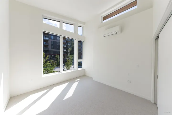 Full-height windows with transom details, light-toned carpeting, and a wall-mounted climate control unit