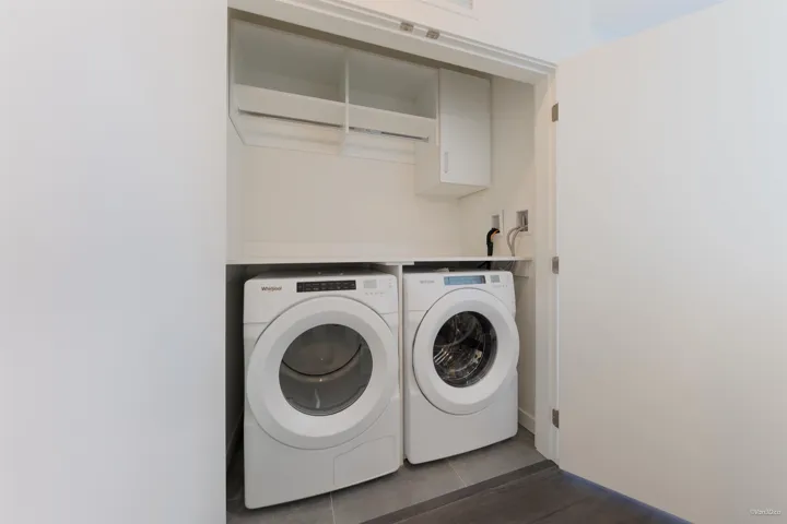 Dedicated laundry closet featuring a built-in shelf, hanging rods, and integrated appliances