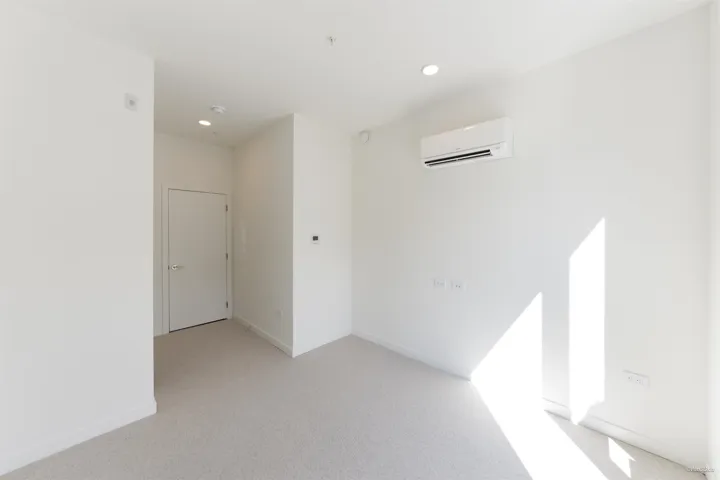 Neutral color palette with light gray carpeting, crisp white walls, and recessed lighting