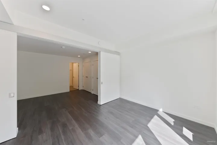 Wide plank wood-finish flooring, recessed ceiling lighting, and crisp white walls throughout