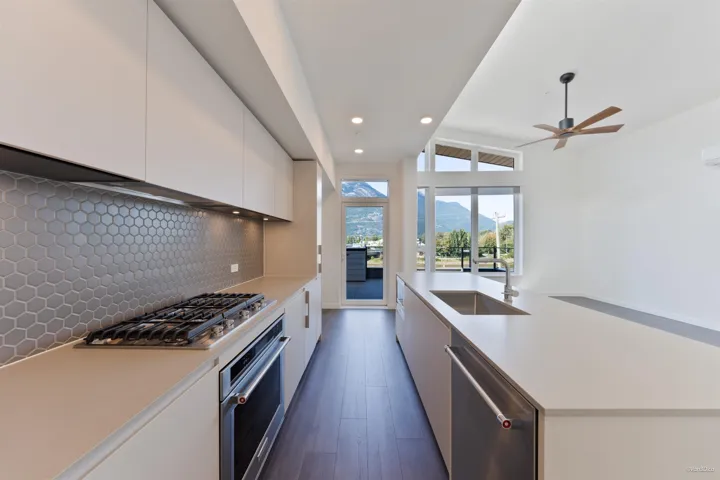 Contemporary kitchen featuring flat-panel cabinetry, a hexagon tile backsplash, and a built-in gas range
