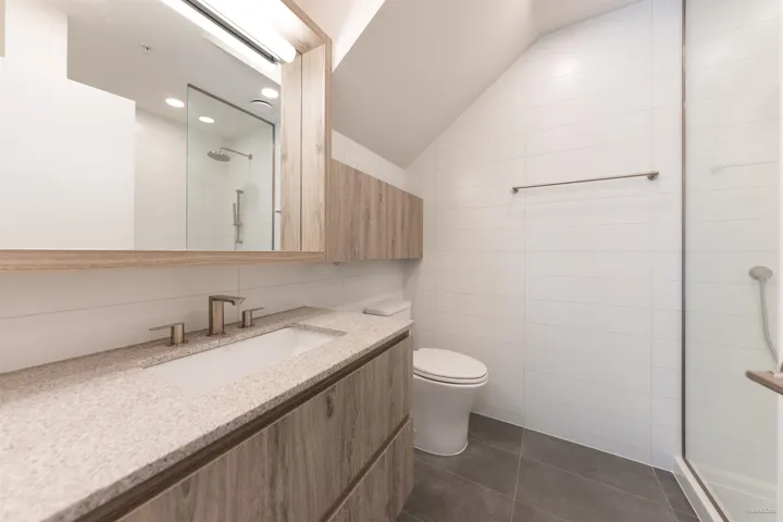Vanity with integrated sink, wood-finish cabinetry, and brushed nickel fixtures