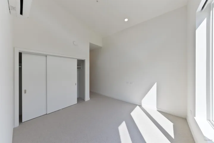 Recessed ceiling lighting, light-colored carpet flooring, white walls, and a large window