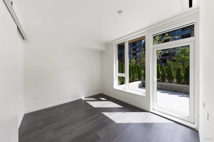 Wide plank wood-finish flooring, white walls, and a white framed glass door leading to a private patio