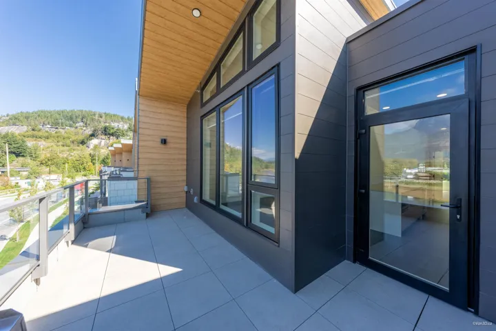 Outdoor balcony featuring tiled flooring, glass panel railing, and wood-finish ceiling
