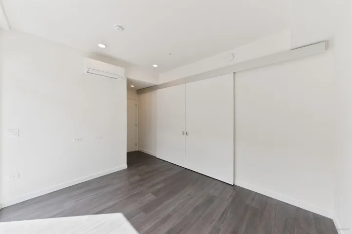 Recessed lighting, wood-finish flooring, white walls, and a split-system air conditioning unit