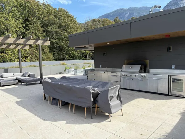 Expansive rooftop patio featuring a built-in stainless steel outdoor kitchen, integrated outdoor grill, and a contemporary pergola structure