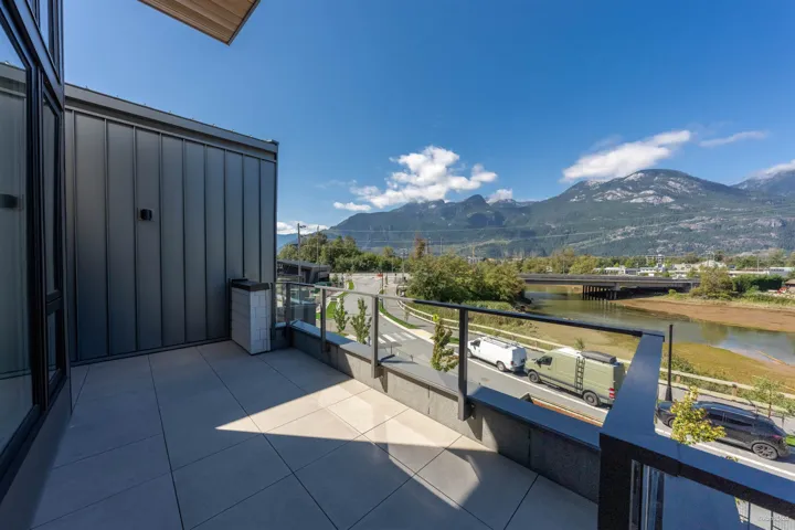 Exterior balcony with tile flooring, glass panel railing, and mountain scenery