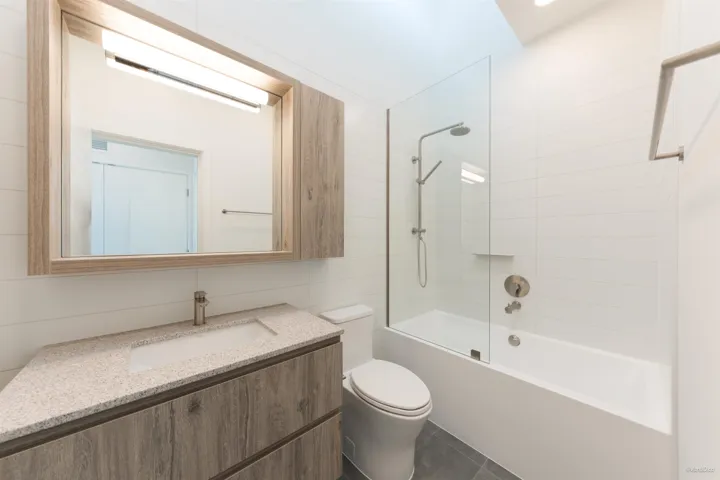 Floating vanity with integrated sink, stone-finish countertop, and wood-finish cabinetry