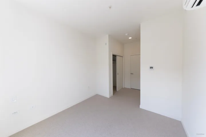 Carpeted room featuring recessed lighting, a sliding closet door, and a wall-mounted climate control unit