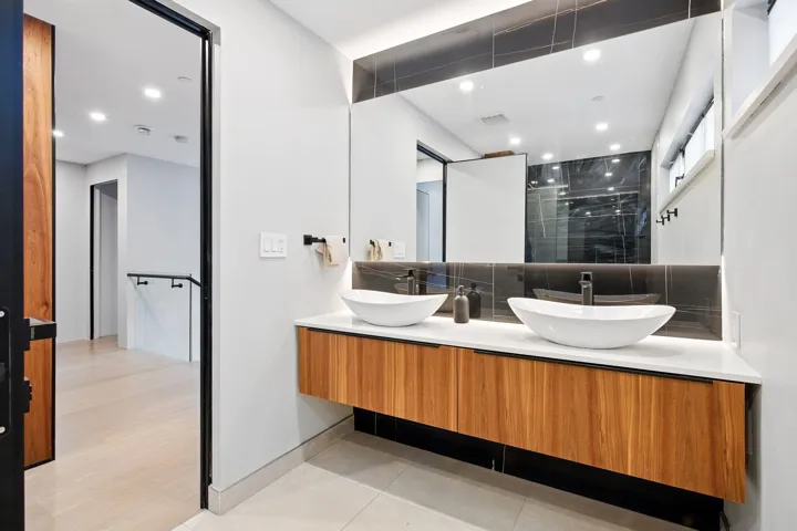 Bathroom featuring a stall shower, double vanity, backsplash, baseboards, and tile patterned flooring