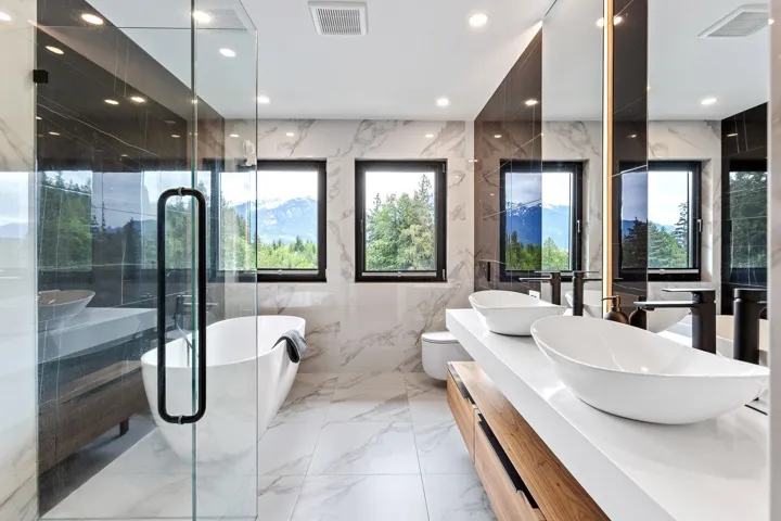 Bathroom featuring marble tiled floors, stone wall, a soaking tub, double vanity, and recessed lighting