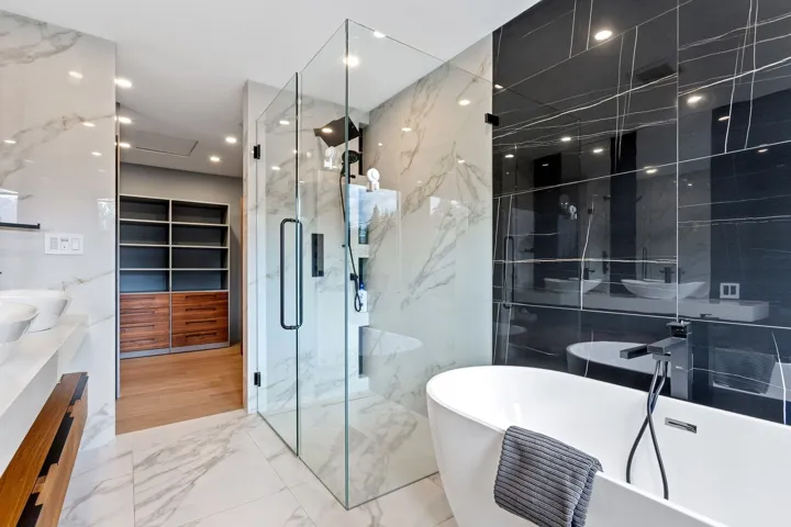 Full bath featuring a marble finish shower, a freestanding bath, marble tiled floors, and vanity