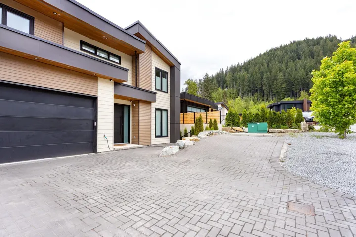 View of front of home with decorative driveway, a garage, and a forest view